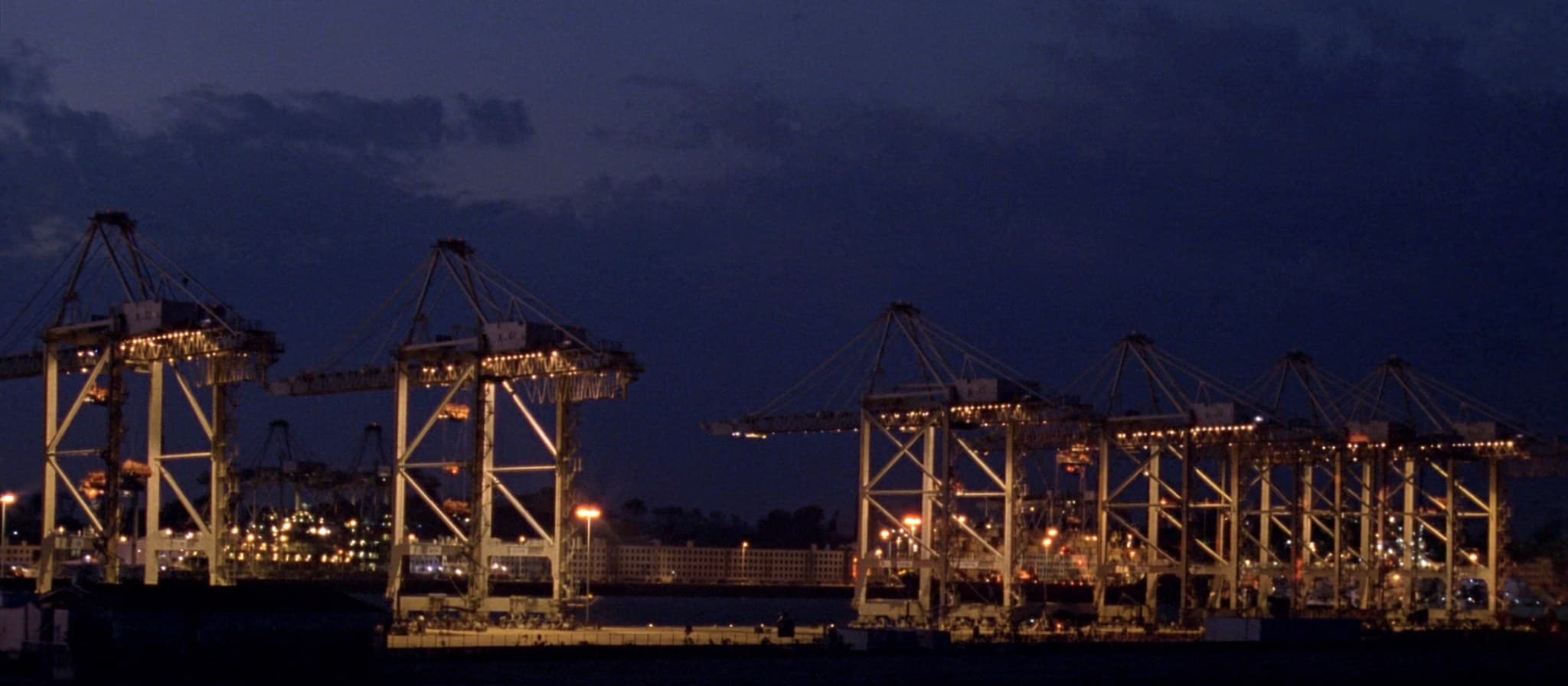 Lamu Port container terminal at dusk, gantry cranes lit against the night sky